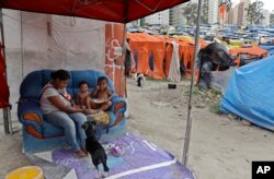 In this Monday, Dec. 11, 2017 photo, a mother feeds lunch to her children in the squatter community coined "Povo Sem Medo," or Fearless People