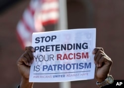 FILE - A man holds a placard during a protest Aug. 13, 2017, in Plymouth, Massachusetts.