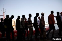 FILE - Migrants intercepted aboard a dinghy off the coast in the Mediterranean Sea leave a rescue boat upon arrival at the port of Malaga, southern Spain, July 7, 2018.