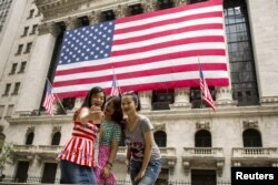 FILE - Chinese tourists take a selfie outside of the New York Stock Exchange, in New York, July 8, 2015.