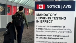 FILE - A traveler walks past a "Mandatory COVID-19 Testing" sign at Pearson International Airport during the coronavirus disease pandemic in Toronto, Ontario, Canada, Dec. 18, 2021.