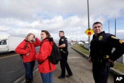 Social workers Staci McCole, left, and Kaitlyn Dowd wait with police officer Kevin Davis, second right, and police Sgt. Mike Braley to cross a busy roadway after checking the overpass below them, a known place for drug use, in Everett, Washington, Feb. 16