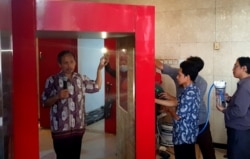 Rektor Institut Teknologi Telkom Surabaya (ITTS), Tri Arif Sardjono, menunjukkan cara kerja tunnel sterilisasi buatan ITTS untuk mencegah penyebaran virus corona (foto Petrus Riski-VOA).jpg