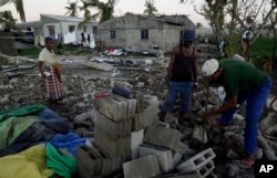 Members of a church salvages bricks from a damaged church building in Beira, Mozambique, Monday, March 25, 2019. The United Nations is making an emergency appeal for $282 million for the next three months to help Mozambique start recovering from the devastation of Cyclone Idai.