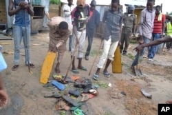 People gather shoes at the site of Sunday night's explosion in Maiduguri, Sept. 21, 2015.