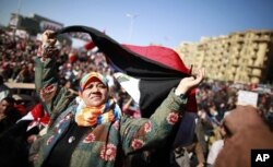 ស្ត្រី​ម្នាក់​កាន់ទង់ជាតិ​អេហ្ស៊ីប​ក្នុង​ពេល​តវ៉ាទាមទារ​ឲ្យ​កងទ័ព​ប្រគល់​អំណាច​ទៅ​ជនស៊ីវិលនៅទីលាន តាហៀរ ក្នុង​រដ្ឋធានីខៃរ៉ូ ថ្ងៃទី២៧ មករា ២០១២។