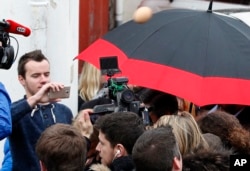Demonstrators launch an egg at Conservative presidential candidate Francois Fillon, who is protected by an umbrella, as he arrives to visit a farm in Arbonne, southwestern France, March 25, 2017.