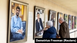 Visitors examine Betsy Ashton's exhibition, "Portraits of Immigrants"