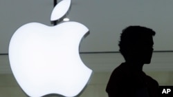 Seseorang berdiri di dekat logo 'Apple' di toko Apple di New York (foto: dok).