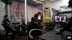 FILE - A group of Hispanic people watch a television broadcast of President Barack Obama's speech on immigration at a Mexican restaurant, Nov. 20, 2014, in Los Angeles. The 5th U.S. Circuit Court of Appeals in New Orleans upheld a Texas-based judge's injunction blocking the immigration initiative.