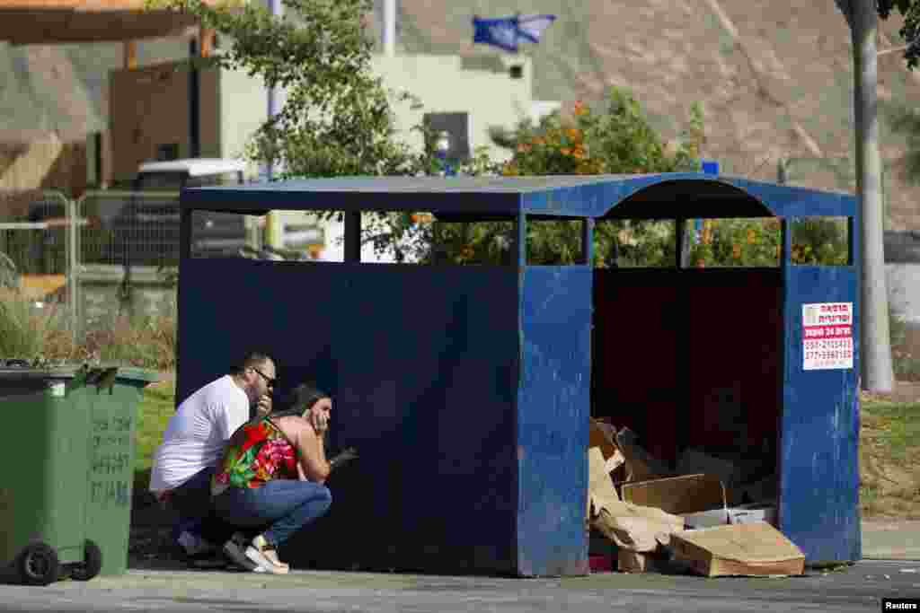 Israelis take cover as an air raid siren warning of incoming rockets sounds in Ashdod July 14, 2014.