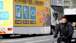 FILE - A truck with a public awareness notice on the omicron coronavirus variant moves along a busy shopping street, in Tokyo, Japan, Jan. 28, 2022.