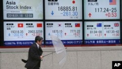 A man walks by an electronic stock board of a securities firm in Tokyo, Jan. 18, 2016. Asian shares skidded lower Monday, following another dismal day on Wall Street, as investors looked ahead to Chinese economic growth figures. 