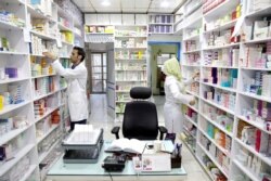 FILE - Pharmacists pick medicine from shelves in a drugstore in Tehran, Iran, June 19, 2019. From imported chemo drugs and other medicines to those made domestically, many Iranians blame shortages on U.S. sanctions.
