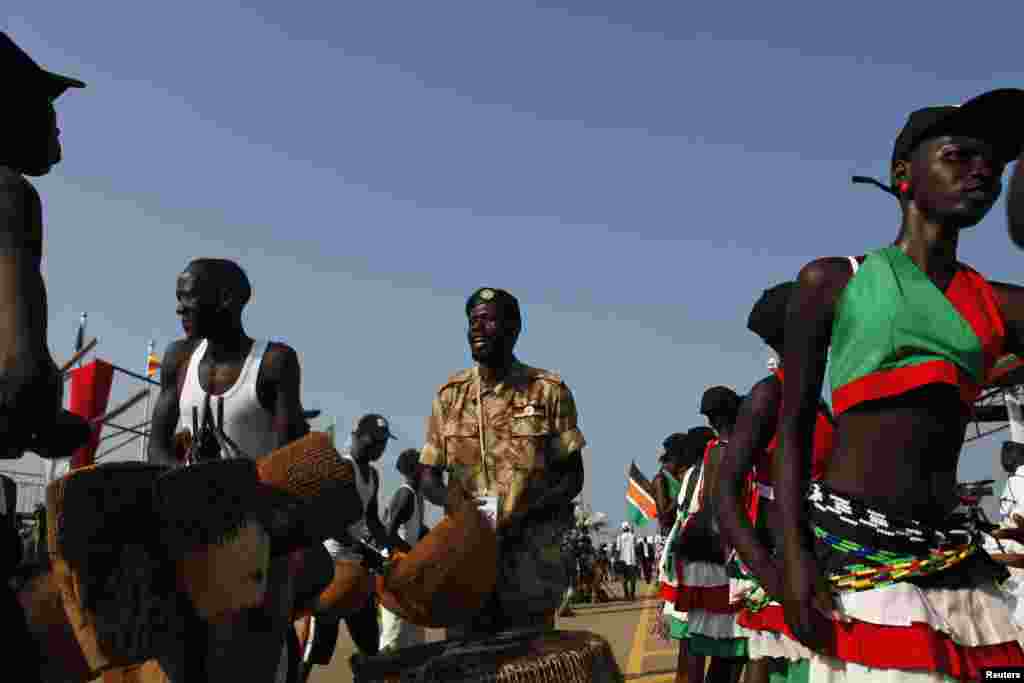 A Sudan People's Liberation Army (SPLA) soldier sings next to traditional dancers during celebrations marking the third anniversary of South Sudan's independence in Juba, July 9, 2014. 