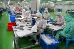 Workers produce protective suits at a factory in Binzhou in China's eastern Shandong province, Feb.y 13, 2020.