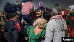 ชายคนหนึ่งอุ้มแม่ขณะข้ามสิ่งกีดขวาง หลังจากการเหยียบกันตายก่อนพิธี "ชาฮีสนัน" ครั้งที่สอง ณ "มหากุมภเมลา" ในเมืองประยาคราช ประเทศอินเดีย 29 ม.ค. 2025 (REUTERS/Adnan Abidi)