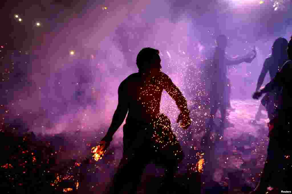A Balinese man holds a burning coconut shell during Mesabetan Api, a purification ritual to enter the holy day of Nyepi, which is a day of silence for self-reflection to celebrate the Balinese Hindu New Year, in Gianyar, Bali, Indonesia.