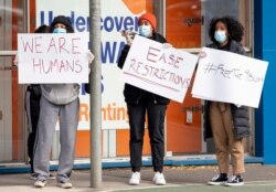 Women hold signs outside housing commission apartments under lockdown in Melbourne, Australia, July 6, 2020.