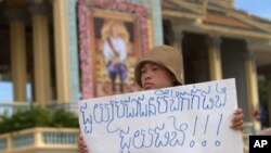 Khek Chan Raksmey of Boueng Kak holds a protest sign as she participates in a rally to ask King Norodom Sihamoni to help release of villagers including her mother in front of Royal Palace in Phnom Penh, Monday, June 11, 2012. The villagers were arrested w