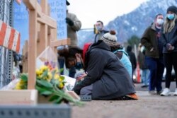 Star Samkus, who works at the King Soopers grocery store and knew the three store employees who were victims in the mass shooting a day earlier, kneels before crosses put up for the victims on the edge of the store's parking lot, March 23, 2021.
