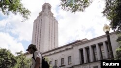 FILE - A student walks past the clock tower at the University of Texas in Austin, Texas, June 23, 2016. On Monday, the state began allowing concealed handguns on public university campuses.