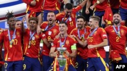 Mshambuliaji wa Uhispania Alvaro Morato akiwa ameshikilia kombe na kusherekea na wachezaji wenzake, Julai 14, 2024. Picha ya AFP