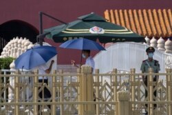 Chinese paramilitary and plainclothes personnel stand on duty at Tiananmen Gate in Beijing, June 16, 2020. Chinese authorities locked down a third neighborhood in Beijing as they rushed to prevent the spread of a new coronavirus outbreak.
