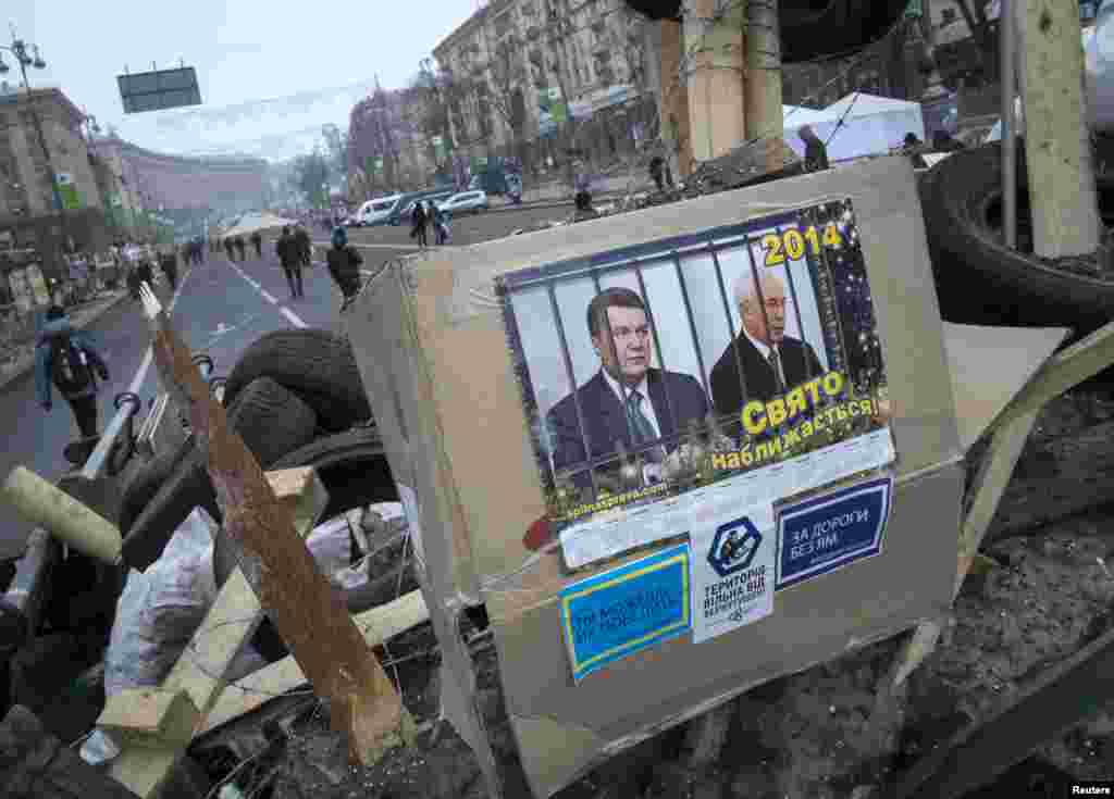 Portraits of Ukrainian President Viktor Yanukovych and Prime Minister Mykola Azarov are seen at a barricade during a rally in central Kyiv, Ukraine, Dec. 20, 2013. 