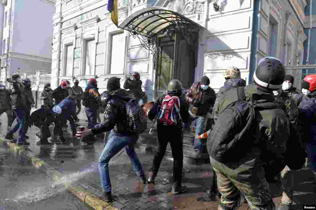 Demonstran anti-pemerintah melemparkan batu ke arah kantor partai pro-presiden di Kyiv (18/2). 