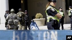 Para petugas berjaga di belakang barikade Departemen Polisi Boston dekat lokasi ledakan pada Marathon Boston, Rabu 17/4. (AP/Julio Cortez)