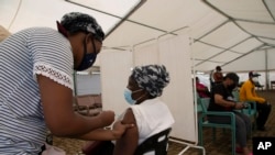 A woman receives a dose of a COVID-19 vaccine at a vaccine center, in Soweto, South Africa, Nov. 29, 2021. 