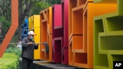 A worker mops the inside of a sign outside a mall in Beijing, China, Aug. 30, 2021.