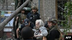 Полицајците помагаат на ранета повозрасна жена за да излезе од оштетена зграда по руски напад во Краматорск, Украина, на 25 септември 2024 година.