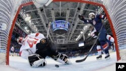 Meghan Duggan of the U.S. celebrates Monique Lamoureux's goal as the puck slides under Goalkeeper Florence Schelling of Switzerland during the second period of the 2014 Winter Olympics women's ice hockey game at Shayba Arena in Sochi, Russia, Feb. 10, 201
