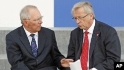 Germany Finance Minister Wolfgang Schauble (L) talks to Eurogroup President Jean-Claude Juncker after posing with other European Union finance ministers for a photo during a meeting of the Economic and Financial Affairs Council in Wroclaw, Poland, Septemb