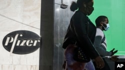 Pejalan kaki berjalan melewati kantor pusat Pfizer di New York, 9 November 2020. (Foto: AP)