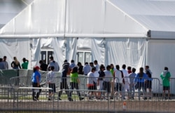 FILE - Detained migrant children from Central America line up to enter a tent at the Homestead Temporary Shelter for Unaccompanied Children in Homestead, Florida, Feb. 19, 2019.