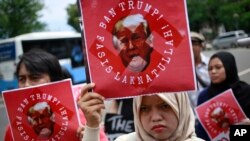 Para aktivis memprotes kebijakan imigrasi Presiden AS Donald Trump di luar Kedutaan Besar AS di Jakarta (4/2). (AP/Dita Alangkara)