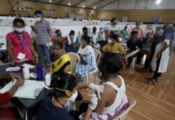 A man receives a dose of COVISHIELD, a coronavirus vaccine manufactured by Serum Institute of India, as others wait for their turn at a vaccination center in Mumbai, India, April 26, 2021.