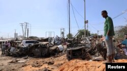 Seorang pria berdiri di lokasi ledakan bom mobil di sebuah pos pemeriksaan di Mogadishu, Somalia, 28 Desember 2019. (Foto: Reuters)