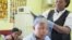 Rita Dantaa, who owns a hair salon in downtown Johannesburg, applies relaxer to her client's hair, May 16, 2014 (Gillian Parker for VOA).