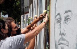 People put white roses on portraits of victims of last year's Beirut port blast as Lebanon marks one year anniversary of the explosion, in Beirut, Lebanon, Aug. 3, 2021.
