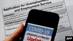 រូបឯកសារ៖ ព័ត៌មាន​ថ្មីៗ​ទាក់ទិន​នឹង​ជំនួយ​សម្រាប់​អ្នក​បាត់បង់​ការងារ​ដោយសារវិបត្តិ​​ជំងឺ​កូវីដ១៩ ត្រូវ​បាន​បង្ហាញ​នៅ​លើ​កញ្ចក់​ទូរស័ព្ទ​ស្មាតហ្វូន​មួយ​គ្រឿង ដែល​ដាក់​នៅ​ពីលើ​ពាក្យ​សុំ​អត្ថប្រយោជន៍​សម្រាប់​អ្នក​បាត់បង់​ការងារ​ ថ្ងៃ​ទី ៨ ខែ​ឧសភា ឆ្នាំ ២០២០។