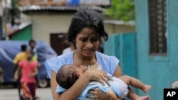 Une sri-lankaise s'éloigne du sanctuaire de St. Anthony, tenant son bébé après que la police a découvert des engins explosifs dans un véhicule garé à Colombo, au Sri Lanka, le lundi 22 avril 2019.
