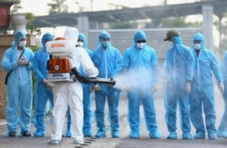 A health worker disinfects arriving Vietnamese COVID-19 patients at the national hospital of tropical diseases in Hanoi, Vietnam on July 29, 2020.