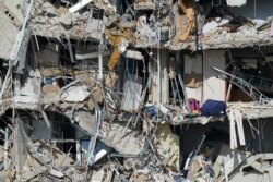Personal belongings are seen amid debris dangling from the remains of apartments sheared in half, in the still standing portion of the Champlain Towers South condo, more than a week after it partially collapsed in Surfside, Fla.