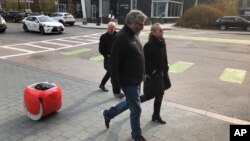 Piaggio Fast Forward CEO Greg Lynn, center, is followed by his company's Gita carrier robot as he crosses a street on Monday, Nov. 11, in Boston, Massachusetts. (AP Photo / Matt O'Brien)