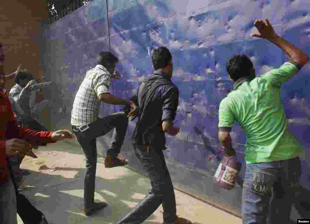 Workers try to break the gate of a garment factory during a protest against the death of their colleagues after a fire in another garment factory killed more than 100 people, in Savar, Bangladesh, November 26, 2012.