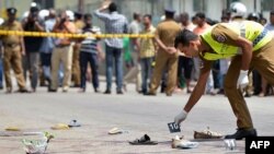 A Sri Lankan police officer examines the scene of a shooting in the capital Colombo, where a woman was killed and 13 others were wounded, July 31, 2015.